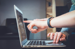 mains pointant un écran du doigt au travail